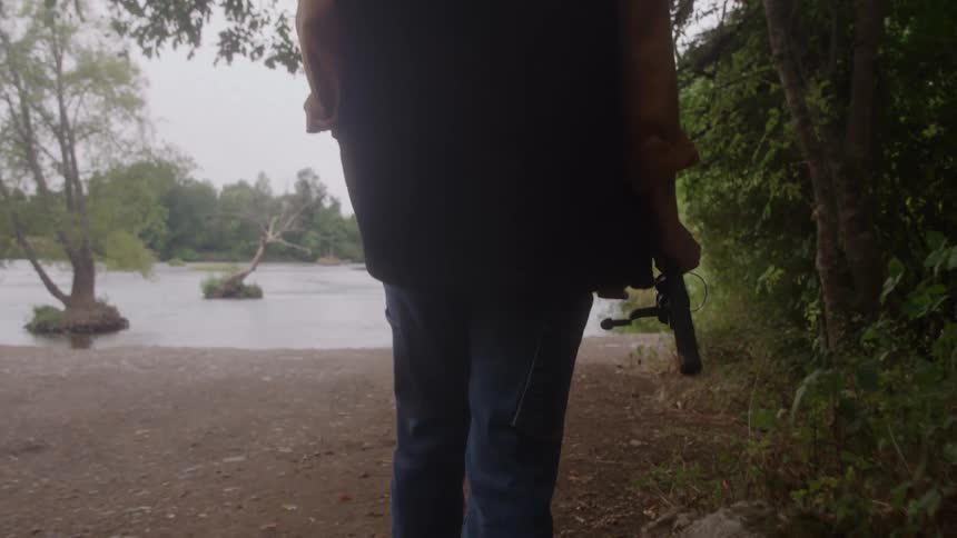 The man is carrying his fishing pole to the river