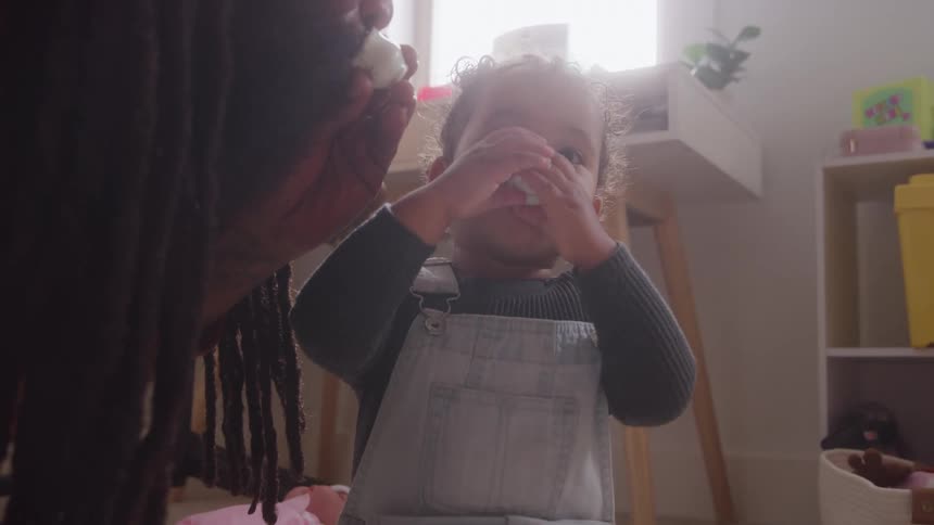 Child imitates the adult as they eat together in the bright room