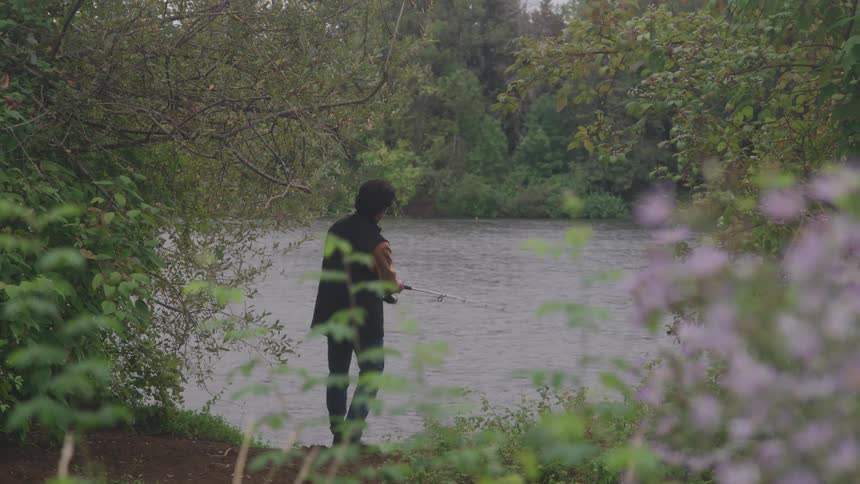 Man standing along the coast casts his fishing line