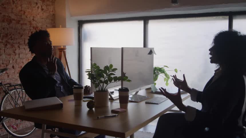 Coworkers talking in an office lit by natural light
