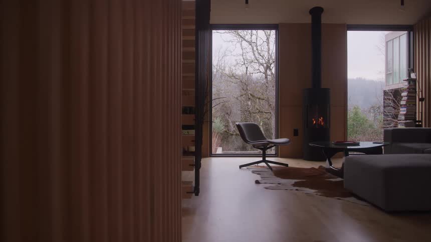 Chair near a window as flames flicker in the living room fireplace