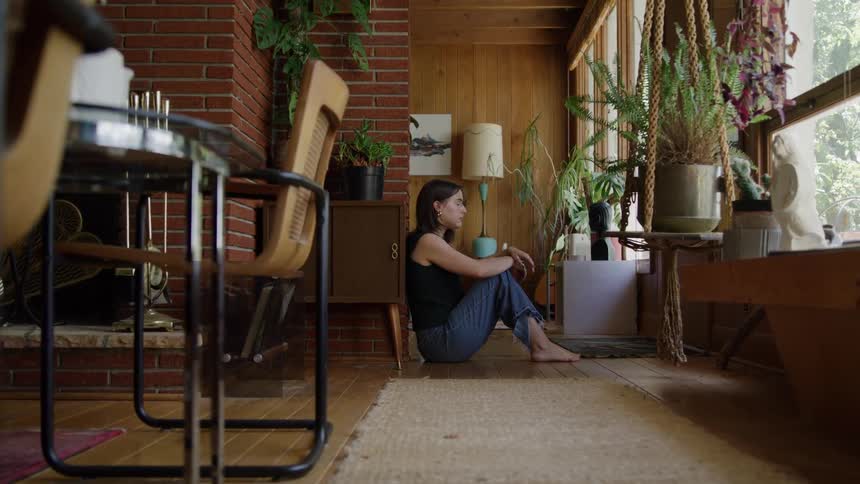 Woman sitting on the floor near the window quietly gazing outside