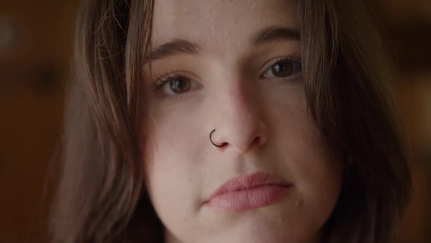 Face of a woman with a calm gaze and a nose piercing