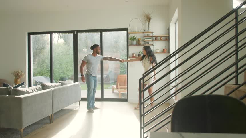A young couple dancing together in a living room during daytime