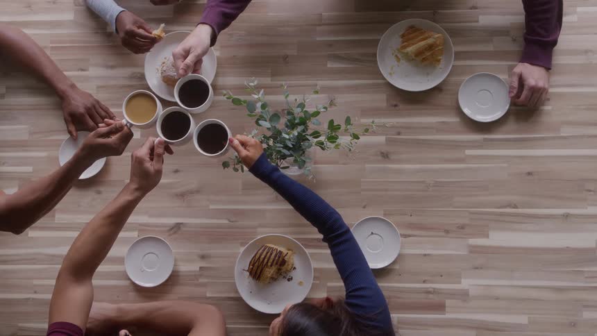 Small group of people toasting with coffee cups indoors during day time