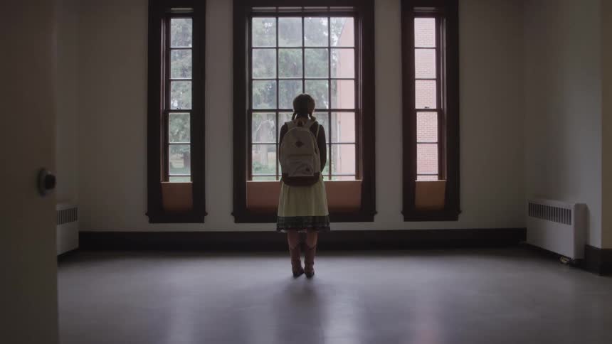 A girl standing and looking out a window