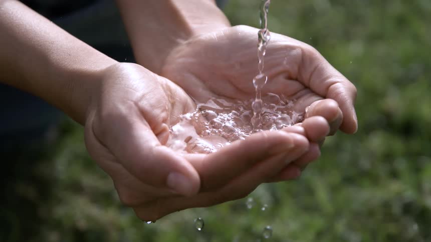 Water pouring into a teen boys cupped hands