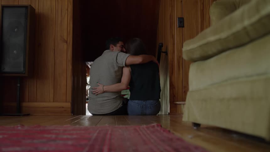 Couple sitting on the wooden floor embracing in a comforting gesture
