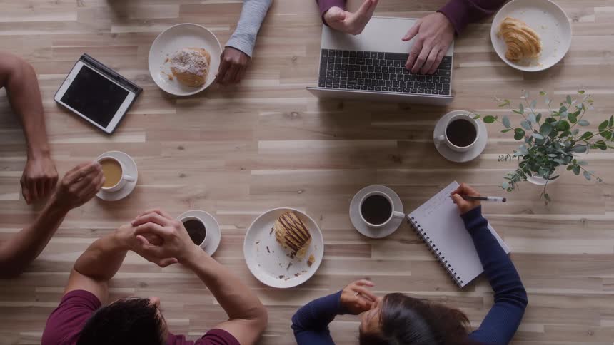 Informal meeting with coffee electronic devices and notes on wooden table