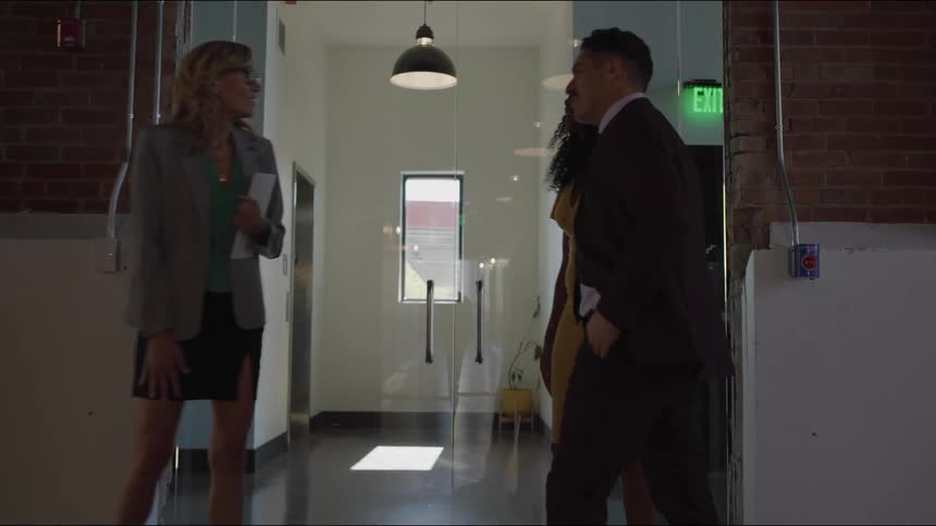 Professionals greet each other in front of the exit door of a corporate building