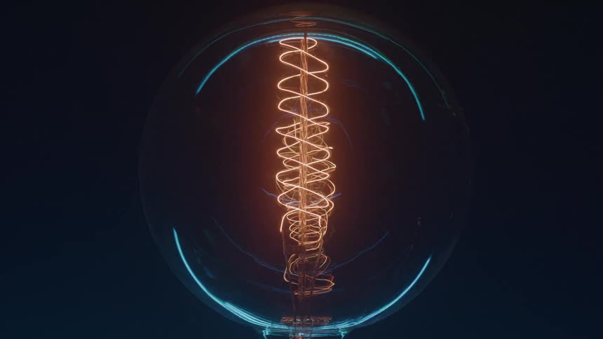 Light bulb with a spiral filament glowing brightly against a dark background