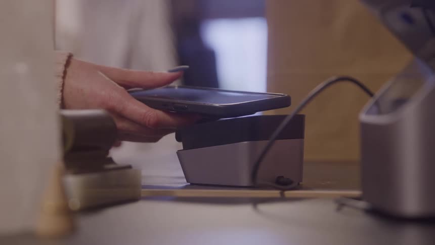 The woman taps her phone to pay in the store