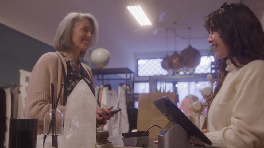 Customer makes a payment while the clerk smiles at the store counter