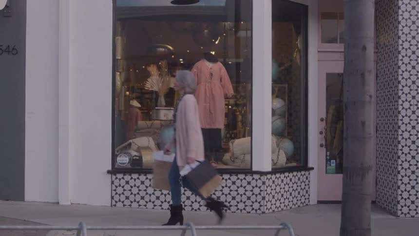 The woman walks by the boutique while carrying bags