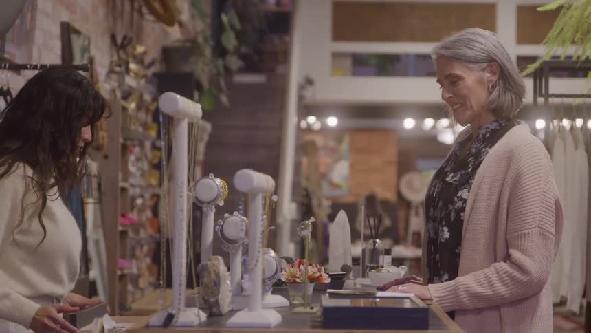 Grayhaired woman making a purchase at an accessory store counter