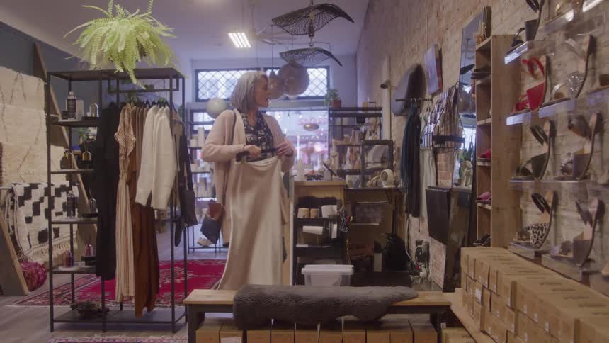 Grayhaired woman holding a piece of clothing while shopping in a boutique
