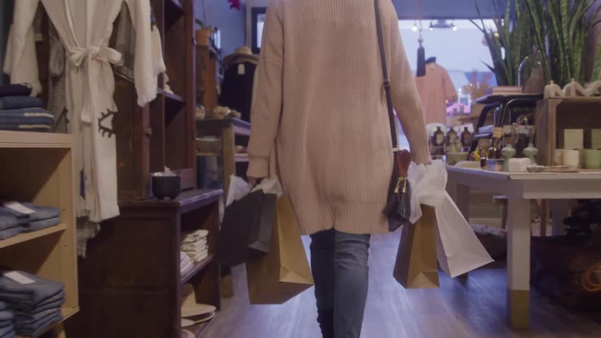 Woman walks through the store carrying multiple shopping bags