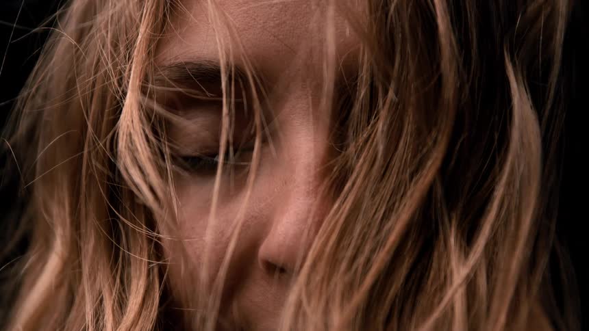 The video is an intimate closeup of a persons hands gently sifting fine sand through their open fingers the scene is at the waters edge on a beach at what appears to be sunset with the warm light illuminating the flow of sand