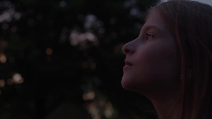 The video is an intimate closeup of a persons hands gently sifting fine sand through their open fingers the scene is at the waters edge at what appears to be sunset with the warm light illuminating the flow of sand