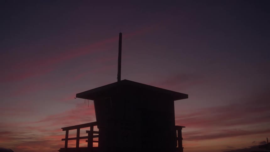 Lifeguard tower silhouetted against a orange sunset sky
