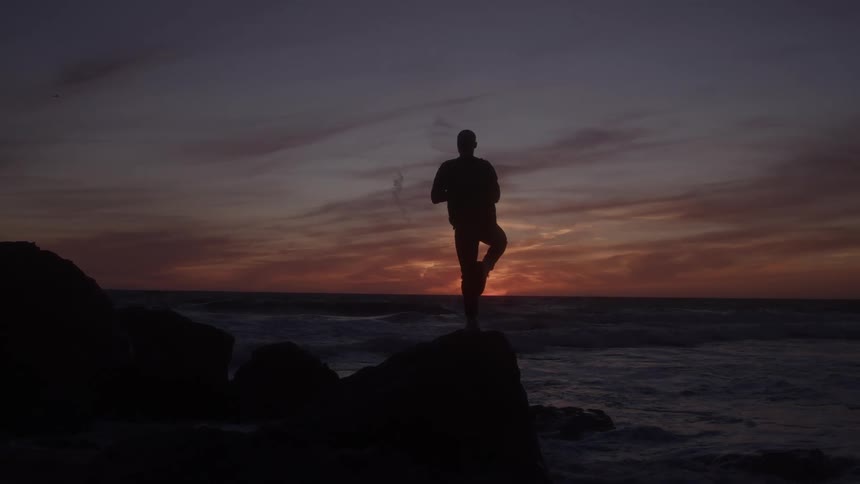The man watches the sun set on the beach
