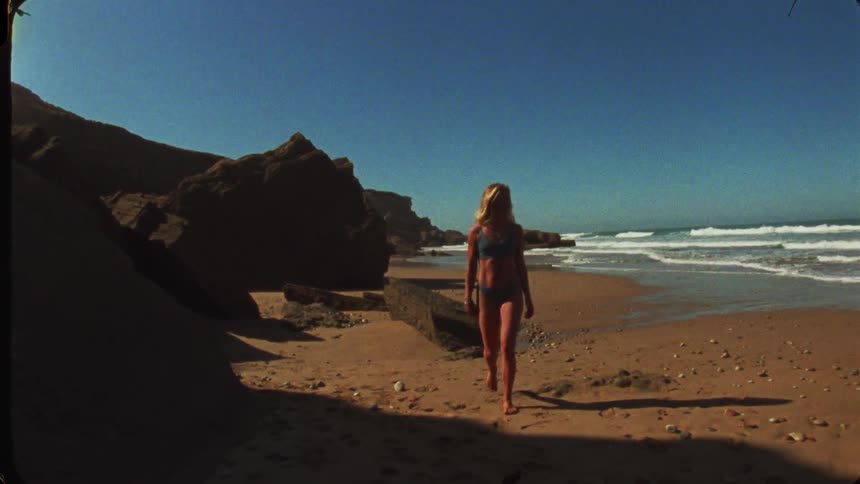 Young woman wearing a bikini as she walks on the beach