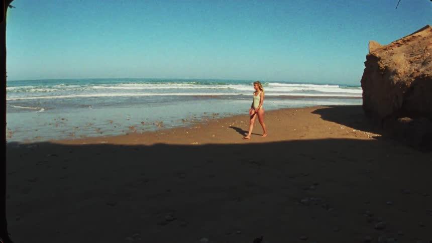 The woman walks across the beach