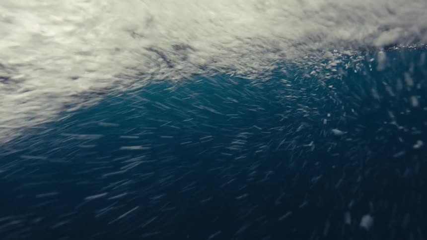 Camera is submerged in water and waves and splashes are crashing on it