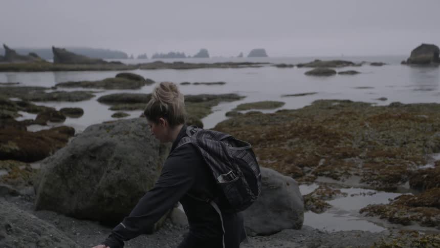 A hiker walks over large rocks and boulders