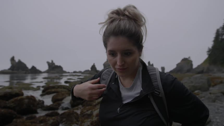 A hiker adjusts her backpack and leans over