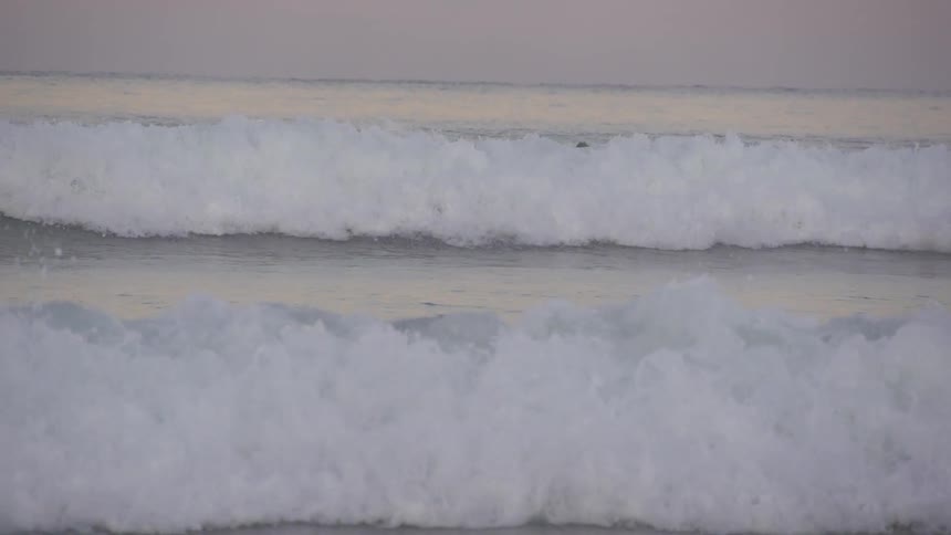 Large, foam capped waves rolling on shore