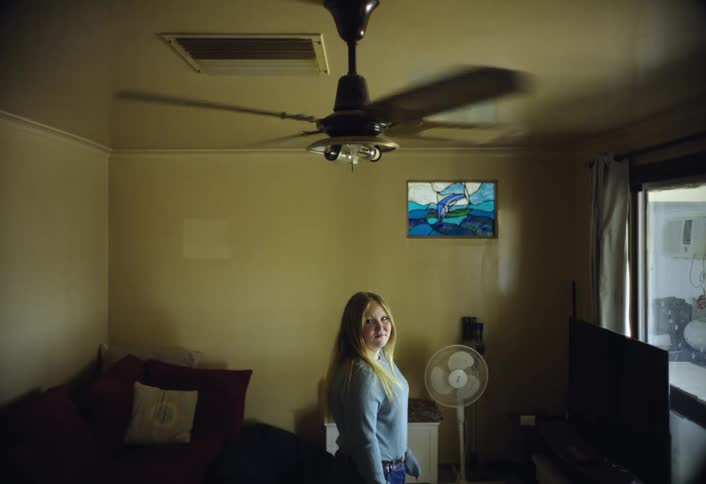 A smiling woman stands by a window in a cozy living room