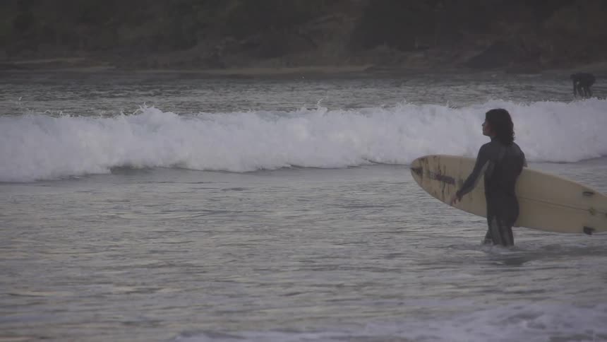 Man with surfboard wading in the ocean