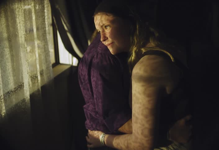 Young woman smiles and looks out the window while hugging another person