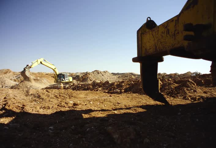 Excavator digging in an arid landscape under a clear sky
