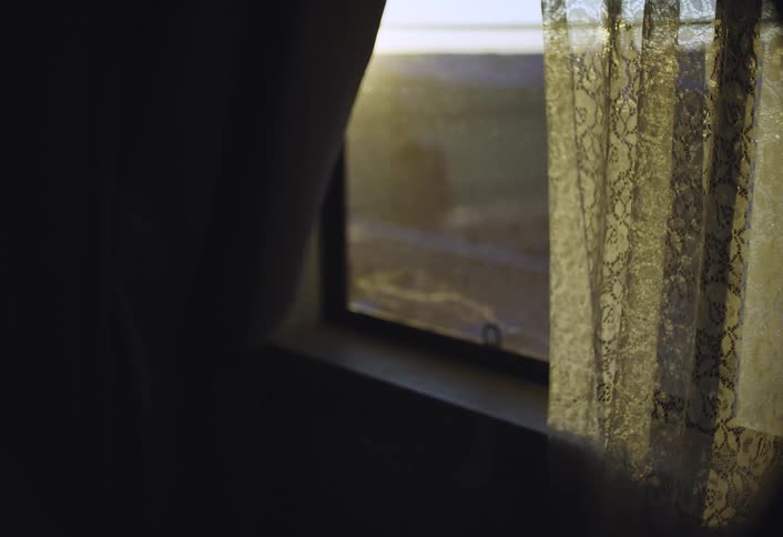 Lace curtains frame the view from an old sunlit window