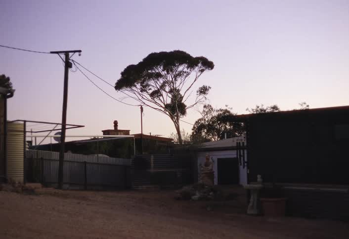 Windchimes sway at the corner of one of the multiple buildings after dusk