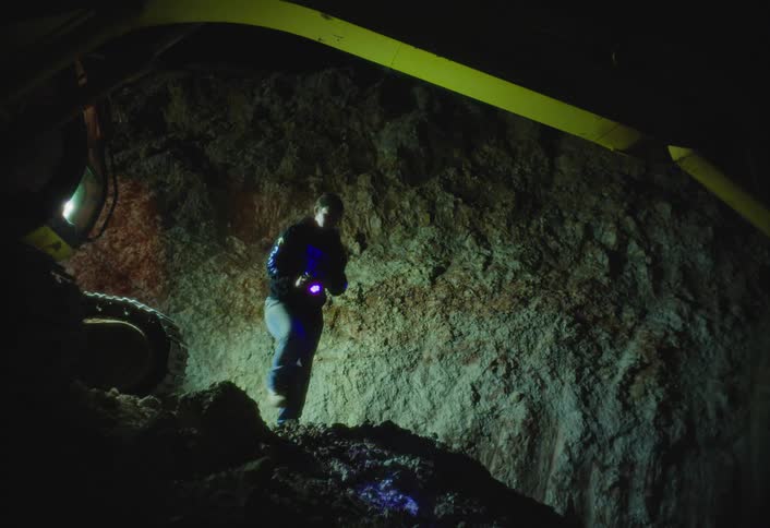 Man holds a flashlight as he walks inside a cave