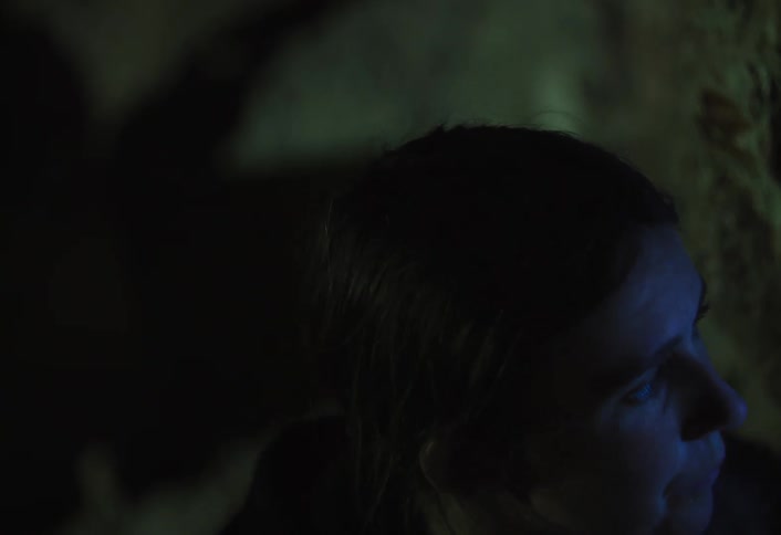 Woman watching intently under blue light in a dark setting