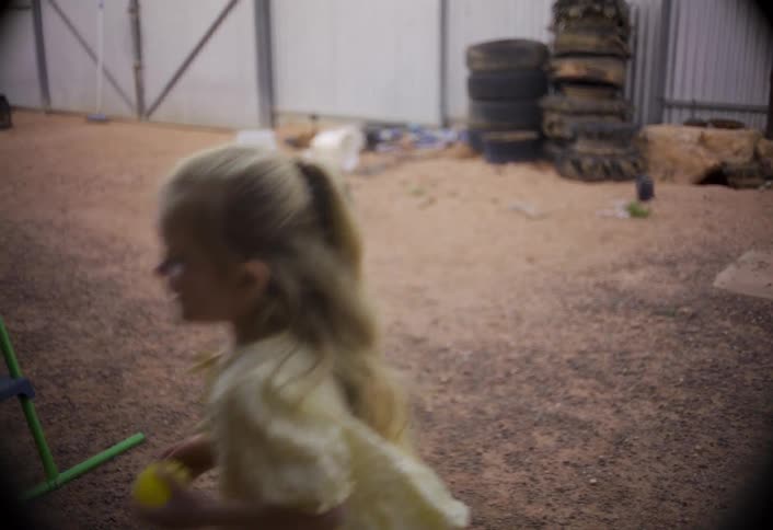 Girl smiling while holding a toy in an outdoor area