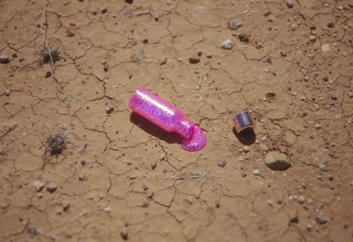 Pink nail polish is spilled on the dirt