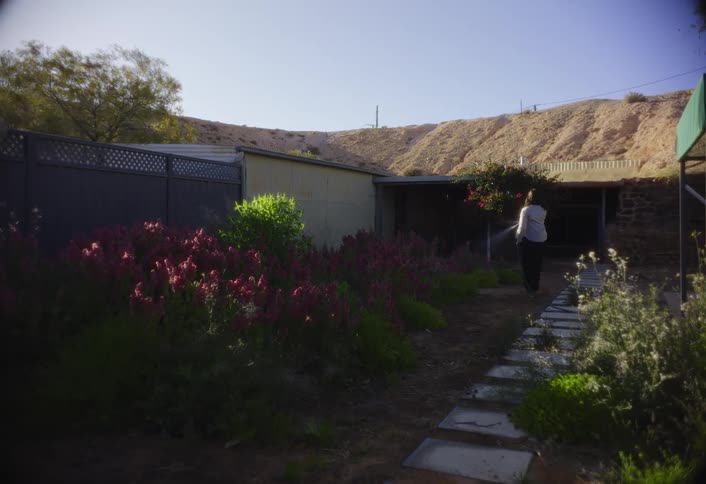 Woman holding a hose as she waters her flower garden