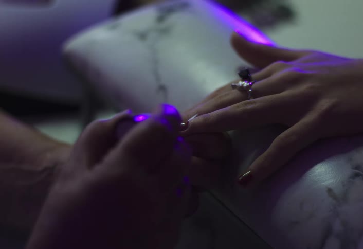 A woman applying nail polish to another womans fingernails inside a beauty shop