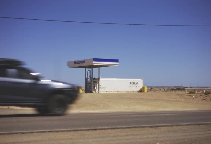 A gas pump by a desert road with a container but no store or payment cabin