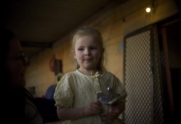 The little girl smiles while raising a piece of candy