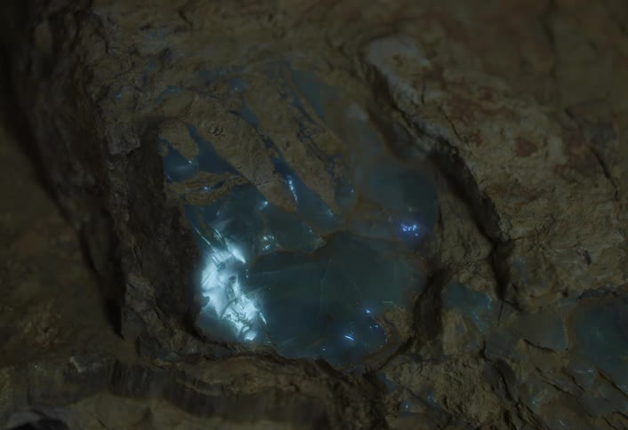 Bluish crystals glowing within the interior of a rock