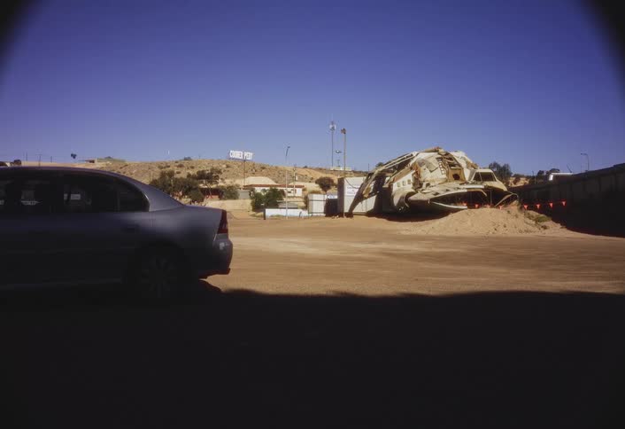 Car parked near an excavator on a pile of sand
