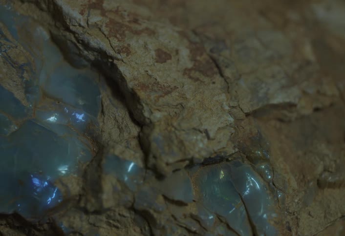 Within the rock there are sections of a translucent pale blue or bluishwhite material that appears to glow slightly or reflect light giving it an ethereal appearance