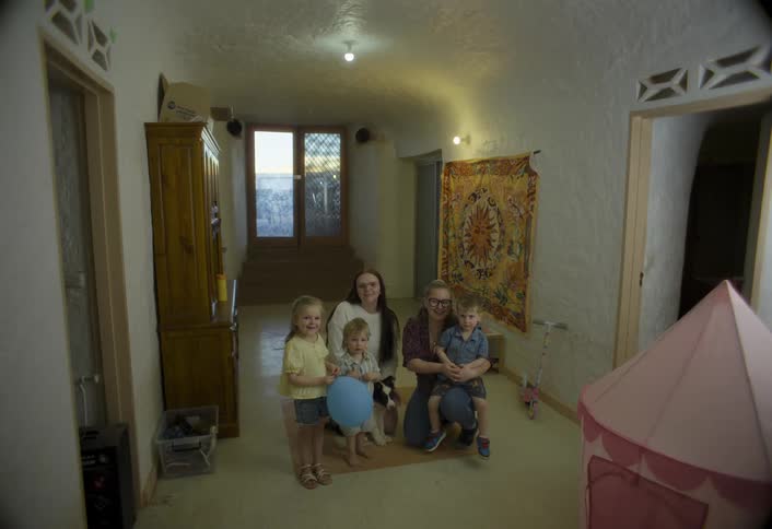 A family with young children poses for a photo inside a warmly lit room