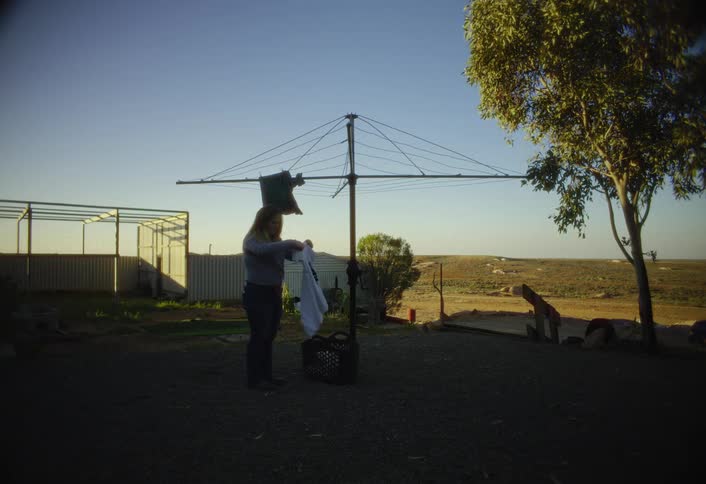 The woman hangs clothes in her yard